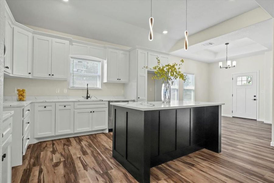 Kitchen featuring white cabinetry, a tray ceiling, dark cabinetry, dark wood finished floors, and decorative light fixtures Kitchen featuring white cabinetry, a tray ceiling, dark cabinetry, dark wood finished floors, and decorative light fixtures
