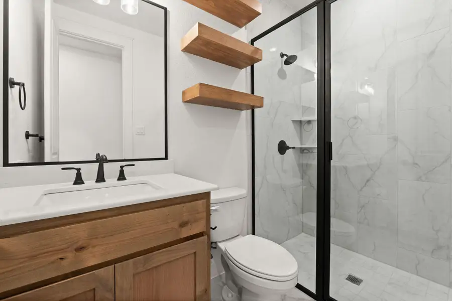 Bathroom featuring vanity and a marble finish shower