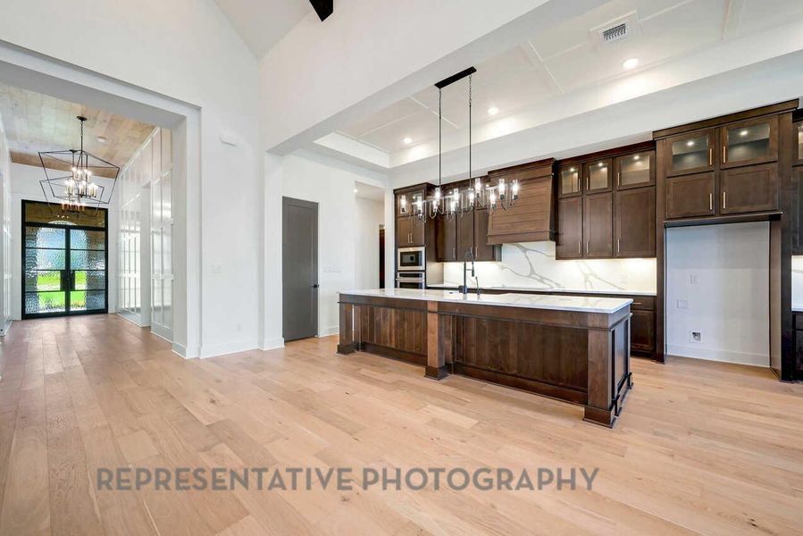 Kitchen with dark brown cabinetry, light wood-style floors, a chandelier, and glass insert cabinets Kitchen with dark brown cabinetry, light wood-style floors, a chandelier, and glass insert cabinets