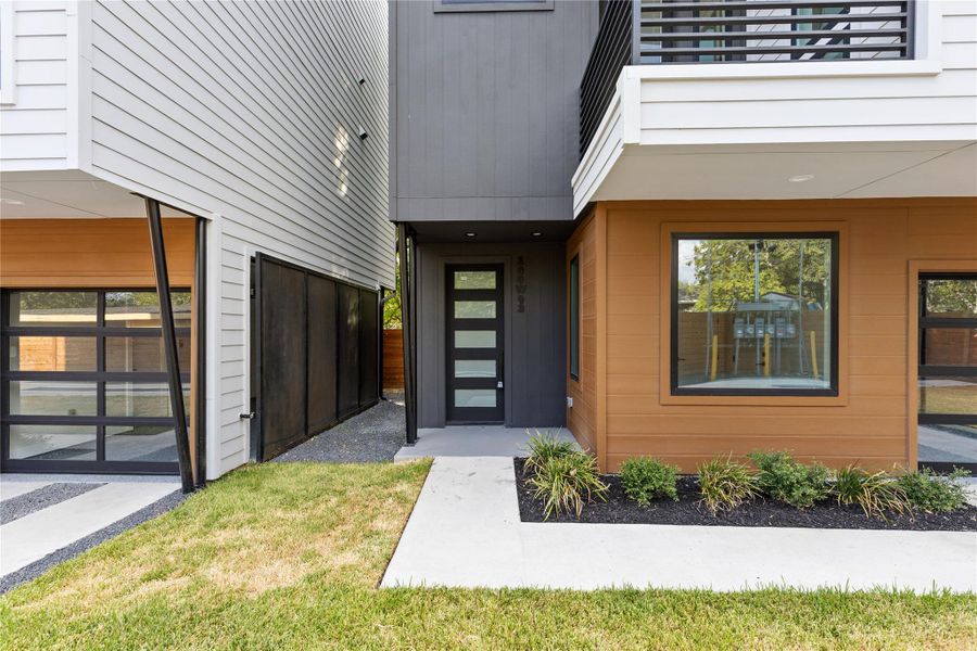 Clean modern architectural lines frame a striking entryway flanked by contrasting siding and neat landscaping.