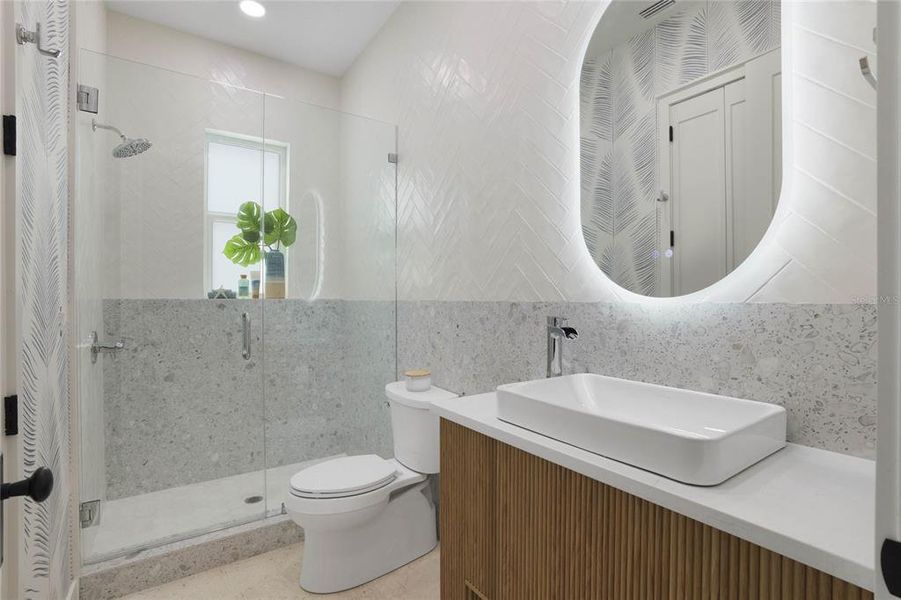 Downstairs full bath with lit vanity mirror and linen closet.