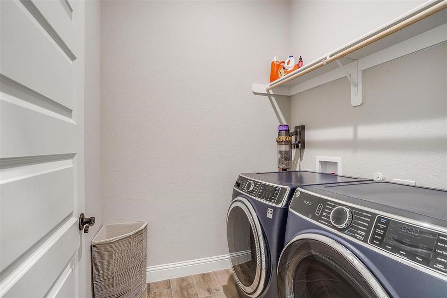 Clothes washing area featuring washer and dryer and light hardwood / wood-style flooring