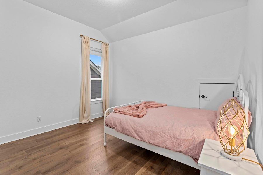 Bedroom with wood-type flooring and lofted ceiling