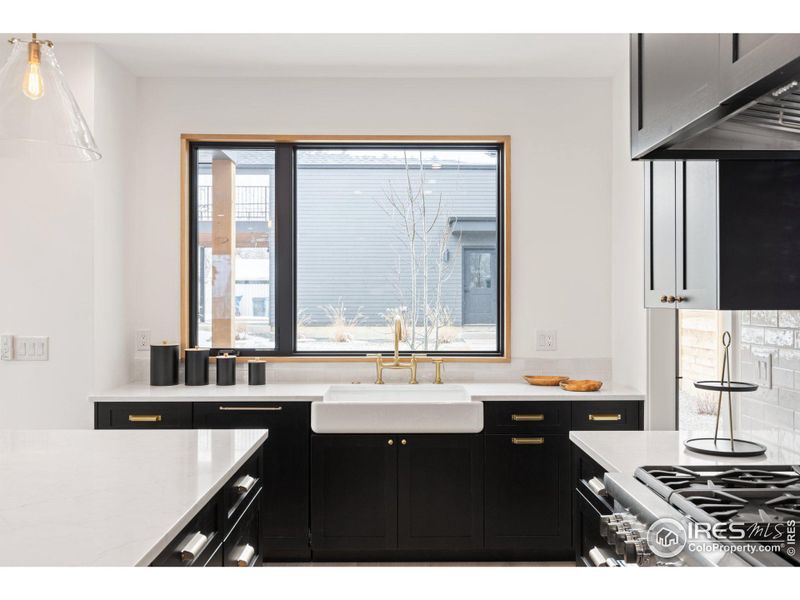 Picture window set over farmhouse sink with direct views to oversized backyard.