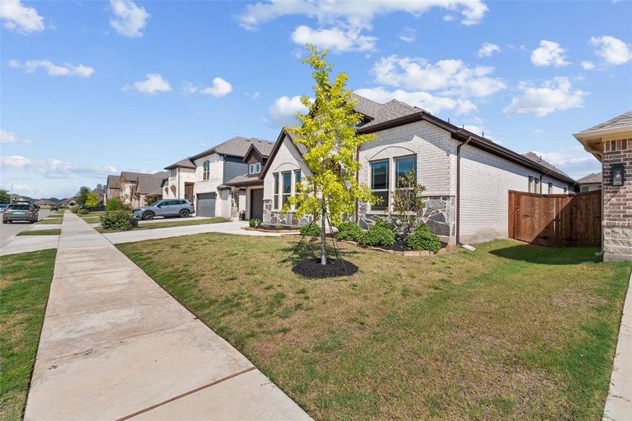 View of front of home with brick siding, a residential view, concrete driveway, and a gate