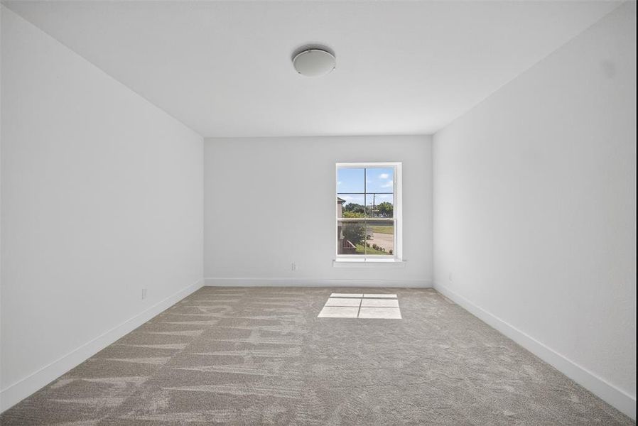 Carpeted spare room featuring baseboards