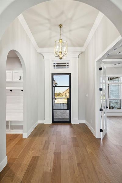 Foyer entrance featuring hardwood / wood-style floors, a wealth of natural light, and crown molding