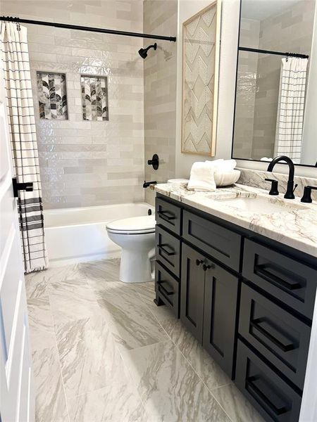 Full bathroom featuring vanity, shower / tub combo, toilet, and marble finish flooring Full bathroom featuring vanity, shower / tub combo, toilet, and marble finish flooring