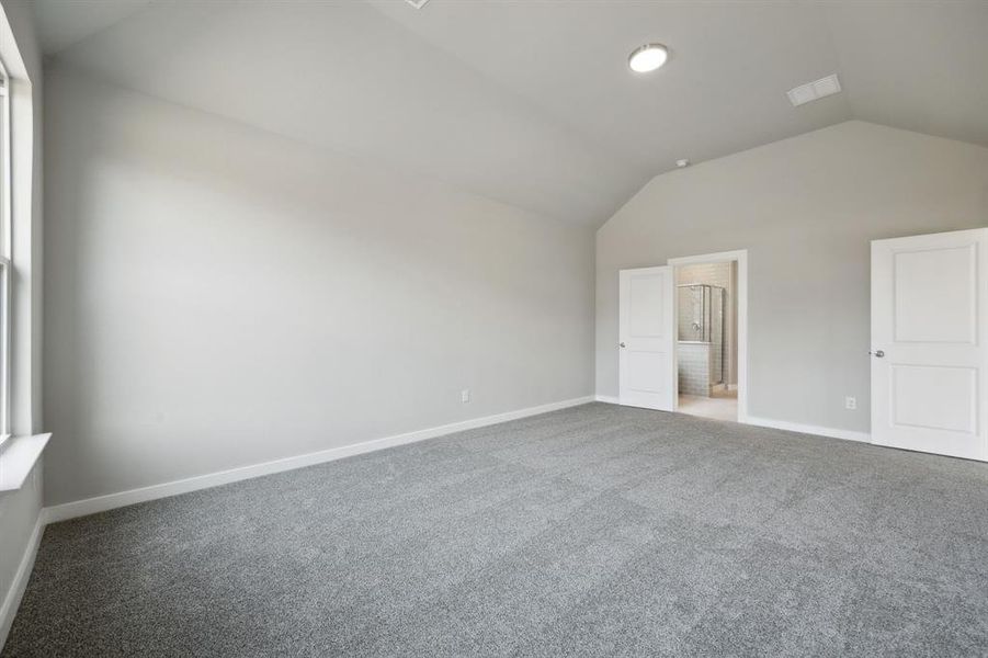 Another view of the primary bedroom showing the ensuite bathroom and door to the main areas of the house.