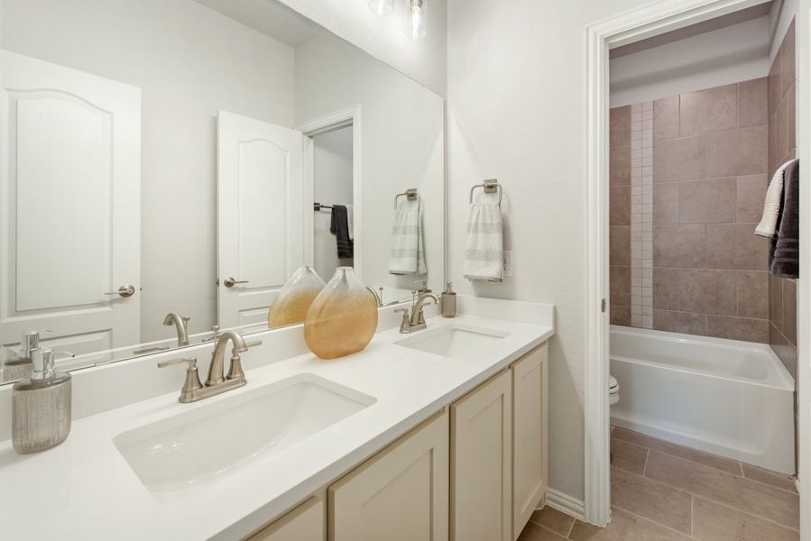 Bathroom with double sink vanity, white countertop, and tiled bathtub and shower combo