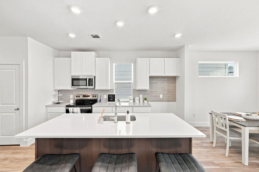 Impressive oversized island provides generous prep space and seating, complemented by quartz countertops, stainless-steel appliances, tile backsplash, and ample cabinetry. Impressive oversized island provides generous prep space and seating, complemented by quartz countertops, stainless-steel appliances, tile backsplash, and ample cabinetry.