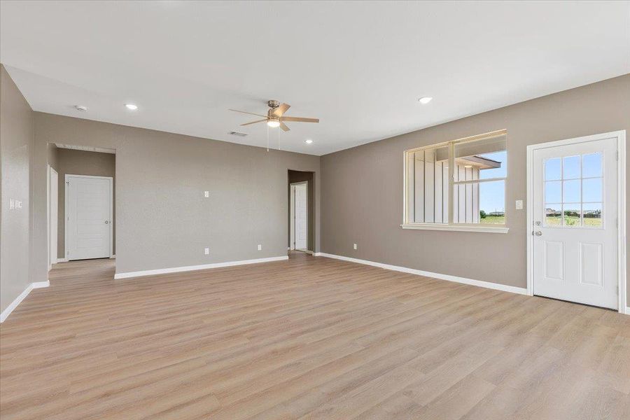 A spacious living area with warm wood-look flooring and abundant natural illumination, perfect for any gathering. A spacious living area with warm wood-look flooring and abundant natural illumination, perfect for any gathering.