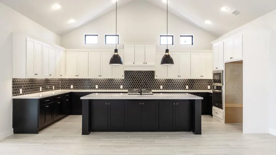 Kitchen featuring dark cabinetry, pendant lighting, tasteful backsplash, white cabinetry, and high vaulted ceiling Kitchen featuring dark cabinetry, pendant lighting, tasteful backsplash, white cabinetry, and high vaulted ceiling