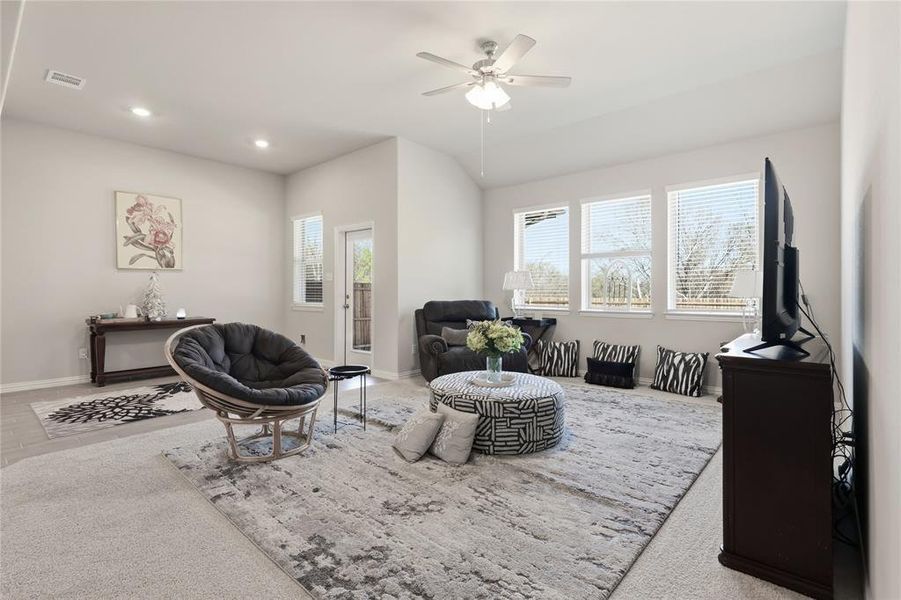 Spacious living area featuring light neutral wall colors, recessed lighting, and a ceiling fan