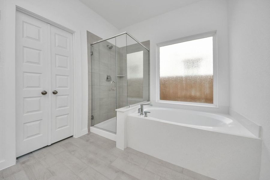 Indulge in a spa-like retreat within the confines of this primary bathroom. Delight in a spacious walk-in shower enveloped in stylish tile surround, unwind in a separate garden tub adorned with custom detailing.
