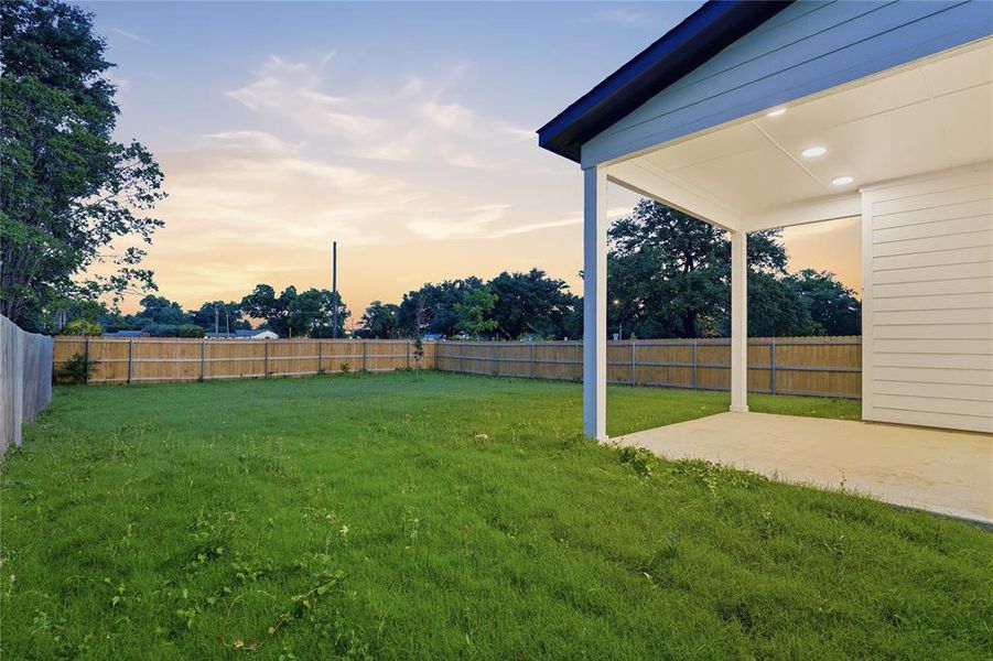 Expansive backyard featuring a manicured lawn, full privacy fencing, and mature perimeter trees Expansive backyard featuring a manicured lawn, full privacy fencing, and mature perimeter trees