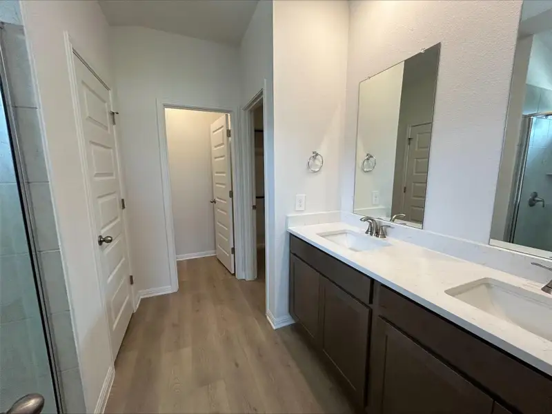 Bathroom with a shower stall, light wood-style floors, and double vanity