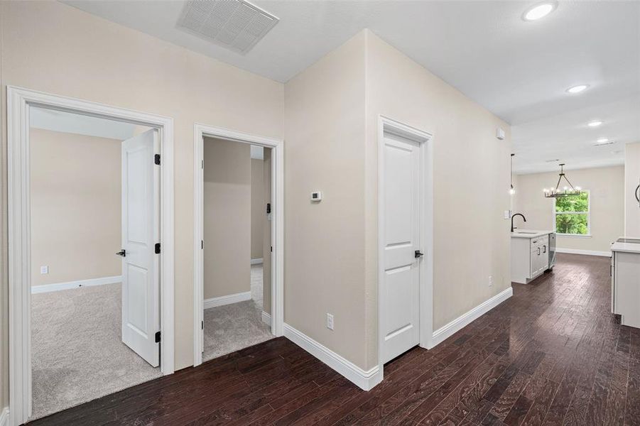 Hallway with rich wood-finish flooring, light neutral wall paint, and white trim