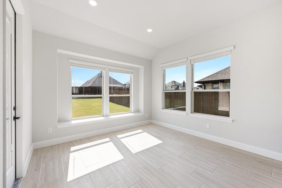 Empty room with light tile floors, white walls, and large windows overlooking a backyard Empty room with light tile floors, white walls, and large windows overlooking a backyard