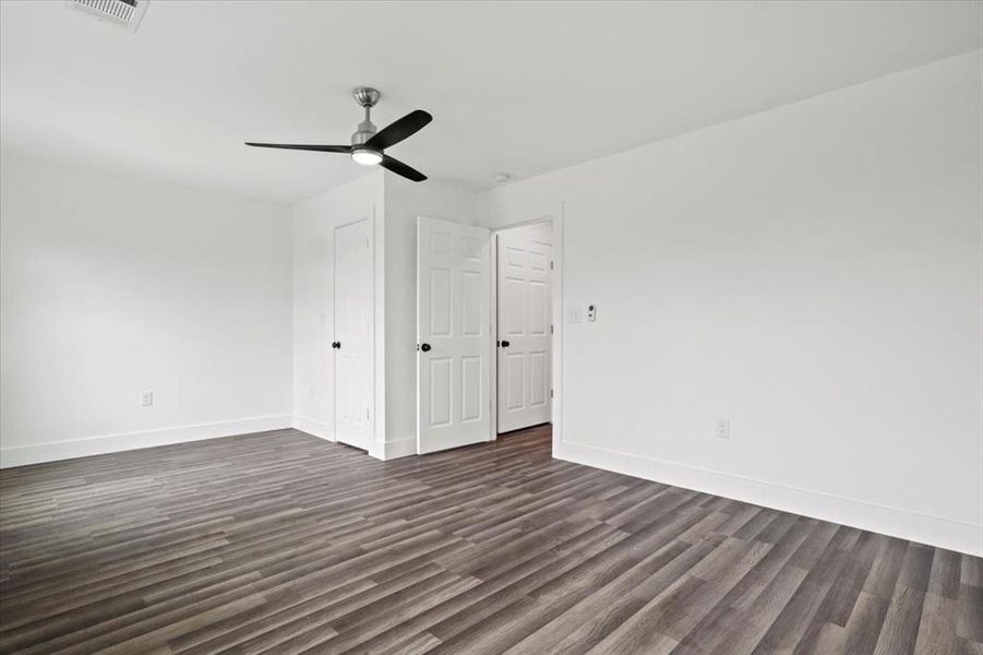 Unfurnished bedroom featuring dark wood-type flooring and ceiling fan