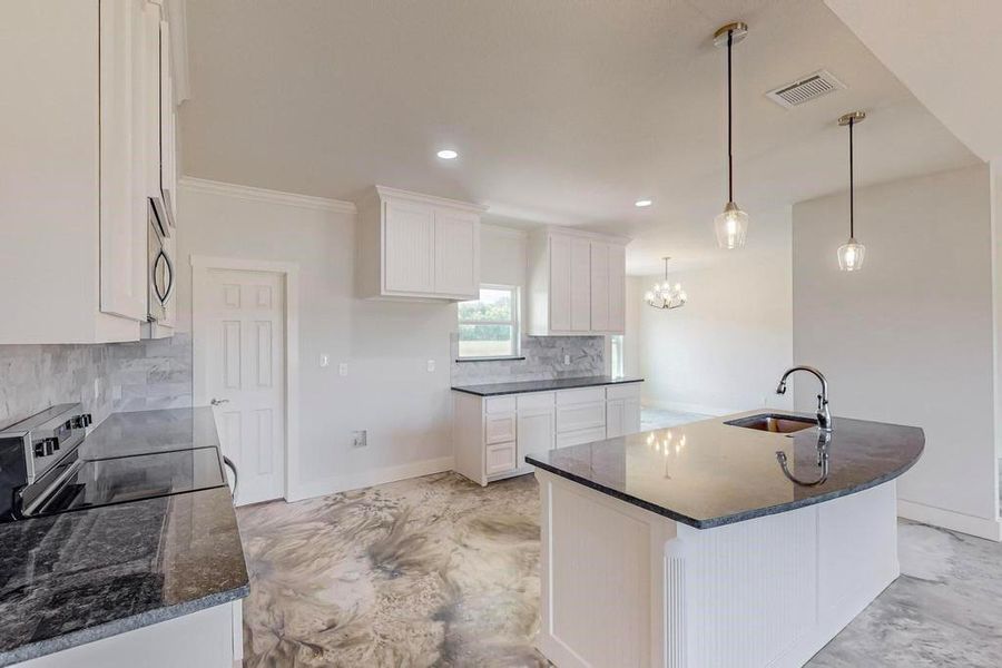 Kitchen featuring electric range, tasteful backsplash, hanging light fixtures, white cabinetry, and sink