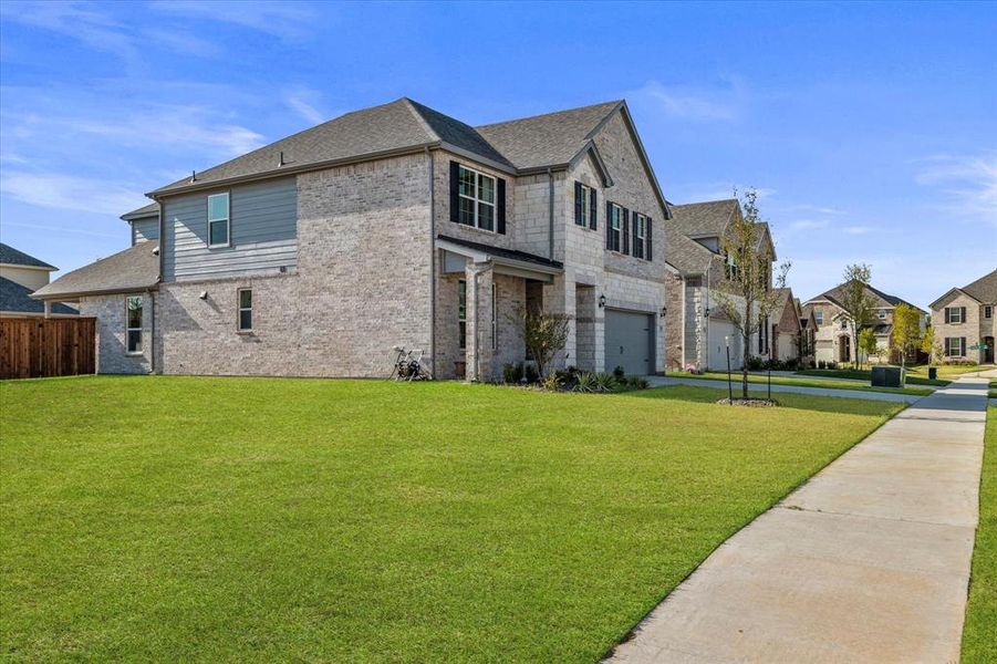 View of front facade featuring brick siding, an attached garage, a front yard, and a residential view