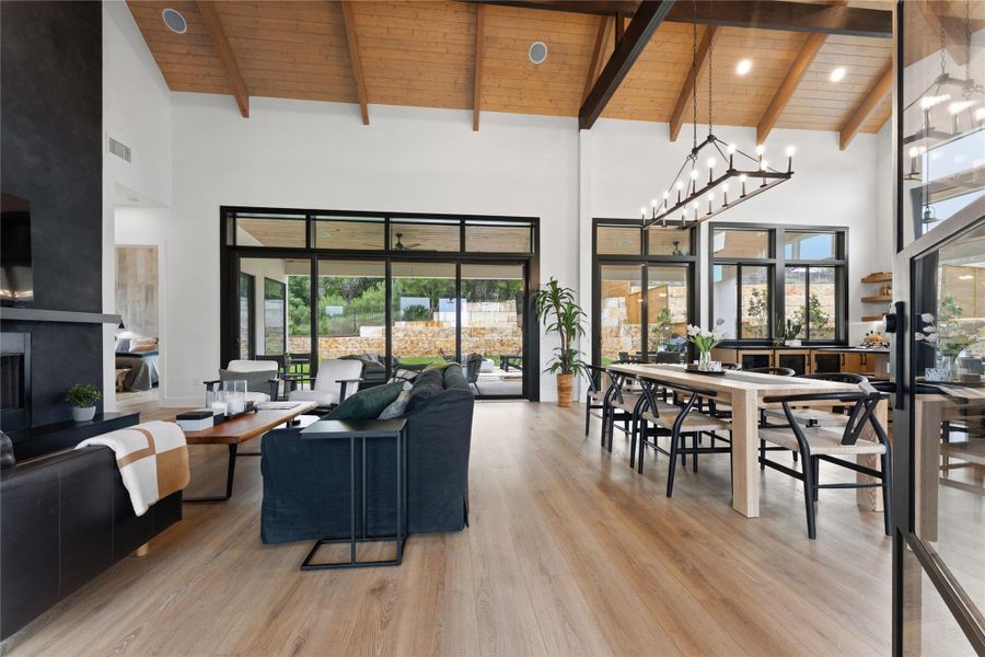 Vaulted wood-plank ceilings with exposed beams, wood-finish flooring, and a contemporary fireplace with a dark finish Vaulted wood-plank ceilings with exposed beams, wood-finish flooring, and a contemporary fireplace with a dark finish
