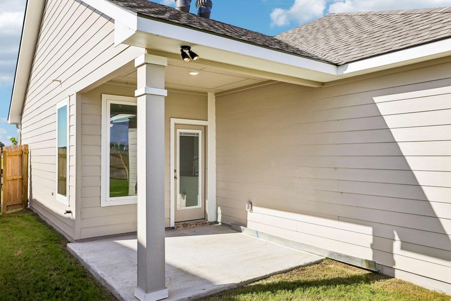 A covered concrete back patio overlooks the yard with horizontal siding and clean architectural lines.