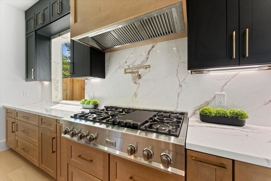 Luxurious 48-inch cooktop with a convenient pot filler and sleek vent hood. Luxurious 48-inch cooktop with a convenient pot filler and sleek vent hood.