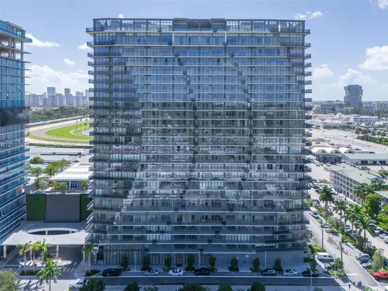 High-rise residential building featuring a glass facade, floor-to-ceiling windows, and wrap-around balconies on each level