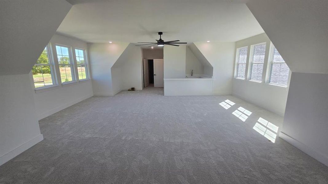 Bonus room featuring vaulted ceiling, carpet, plenty of natural light, and ceiling fan