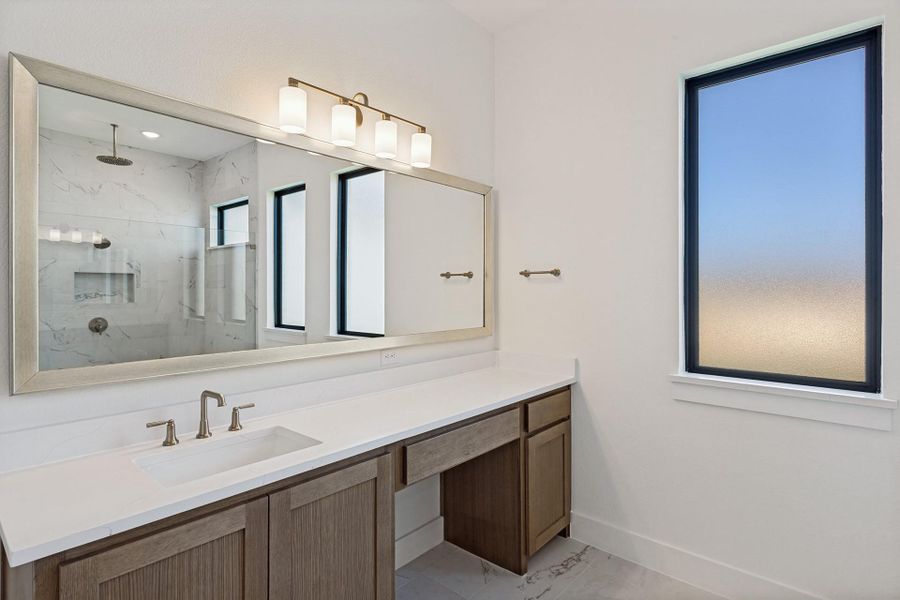 Elegant stone countertops and a spacious vanity create a refined modern bath retreat.