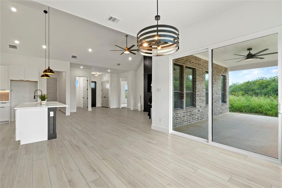 Kitchen featuring open floor plan, a ceiling fan, light countertops, light wood-style flooring, and decorative light fixtures