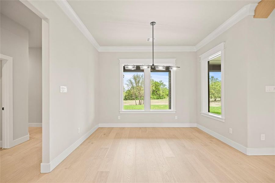 Unfurnished dining area with light wood-style flooring and crown molding Unfurnished dining area with light wood-style flooring and crown molding