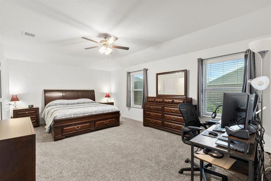 Bedroom featuring a desk, multiple windows, light colored carpet, and ceiling fan