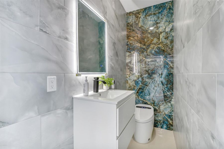 Even the powder room carries a luxury point of view. Stone-pattern tile, an illuminated mirror and a floating vanity give guests a polished space of their own. Even the powder room carries a luxury point of view. Stone-pattern tile, an illuminated mirror and a floating vanity give guests a polished space of their own.