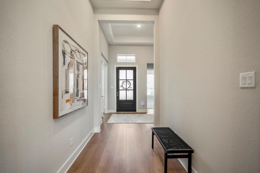 This welcoming foyer brings the drama home with raised ceiling details, warm LVP flooring and a glass-paneled front door that fills the entry with natural light.