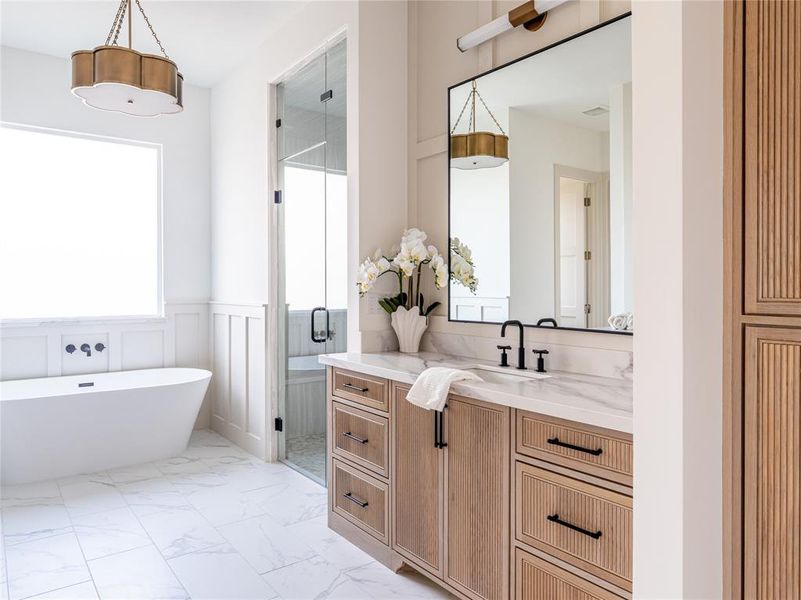 Bathroom featuring vanity, a shower stall, a freestanding bath, a wainscoted wall, and light marble finish floors