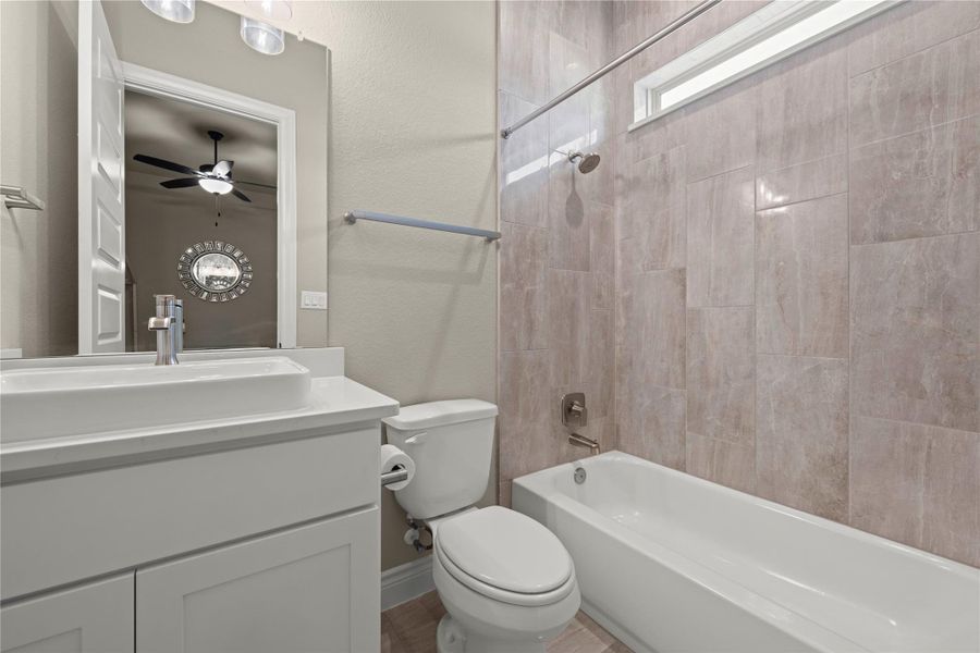 A well-appointed bathroom features a contemporary vanity, toilet, and a bathtub with elegant tile surround and a window. A well-appointed bathroom features a contemporary vanity, toilet, and a bathtub with elegant tile surround and a window.