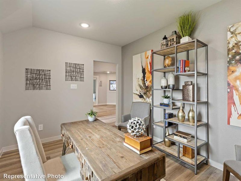 Dedicated office space featuring vaulted ceilings, recessed lighting, wood-finish flooring, and a built-in metal and wood shelving unit