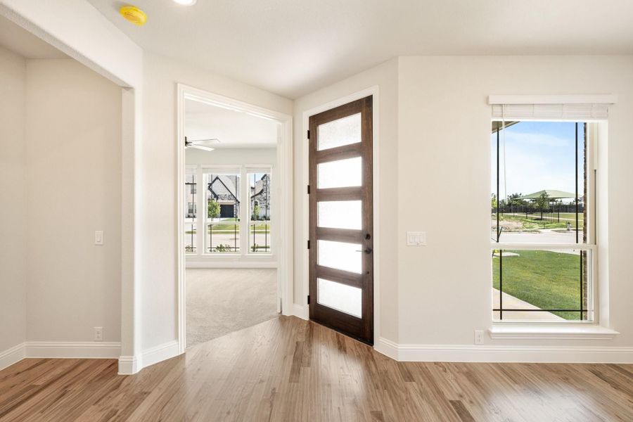 Home entryway with dark wood front door with glass panels and light hardwood floors Home entryway with dark wood front door with glass panels and light hardwood floors