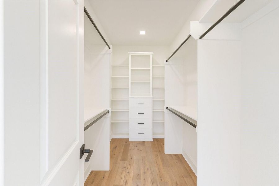 Spacious walk-in closet with custom built-ins, ample shelving, and organized hanging space for a clean and functional design.