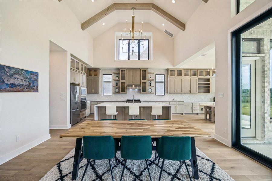 VAULTED CEILINGS AND EXPOSED WOOD BEAMS CREATE AN IMPRESSIVE BACKDROP FOR THE OPEN DINING AREA, WITH THE KITCHEN POSITIONED JUST BEYOND. VAULTED CEILINGS AND EXPOSED WOOD BEAMS CREATE AN IMPRESSIVE BACKDROP FOR THE OPEN DINING AREA, WITH THE KITCHEN POSITIONED JUST BEYOND.