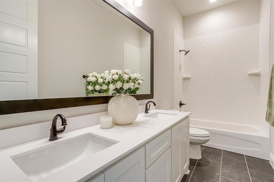 Full bathroom featuring bathing tub / shower combination, tile patterned flooring, toilet, and double sink vanity