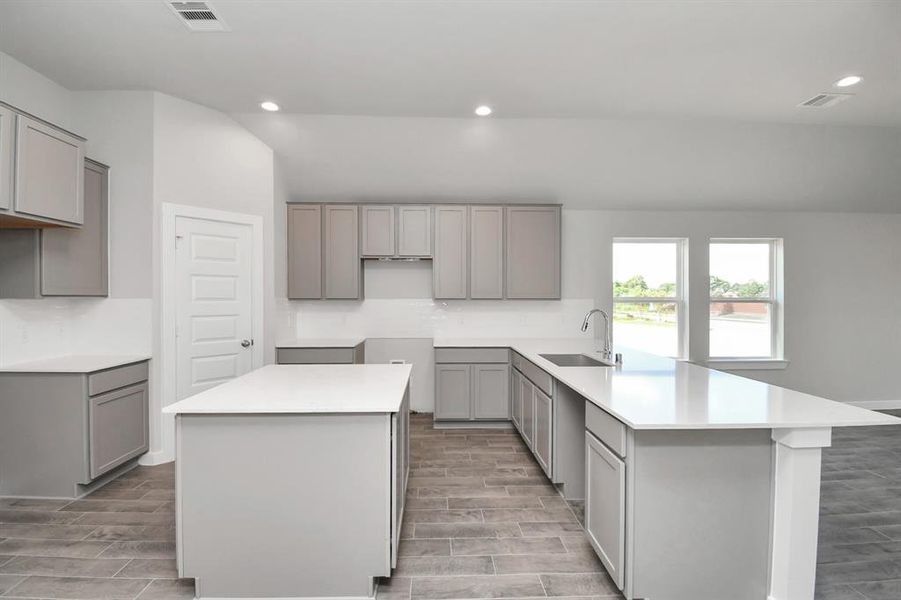 This generously spacious culinary haven features a massive granite island, high ceilings, soft-close cabinets, granite countertops, stainless steel appliances (to be installed), a sleek tile backsplash, and recessed lighting. Representation of completed home with similar plan. Actual color and selections will vary.