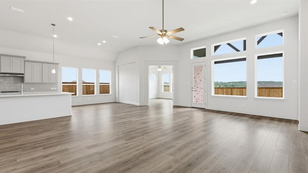 Spacious open-concept living area featuring wood-finish flooring, a contemporary ceiling fan, and recessed lighting