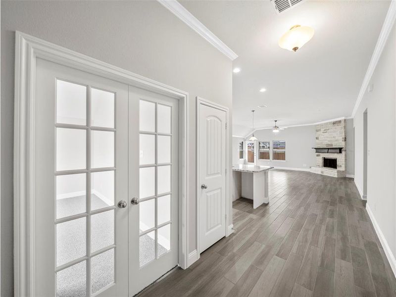 Corridor with ornamental molding, visible vents, wood finished floors, french doors, and baseboards