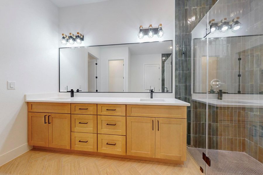 Bathroom featuring double vanity, a shower stall, and parquet floors