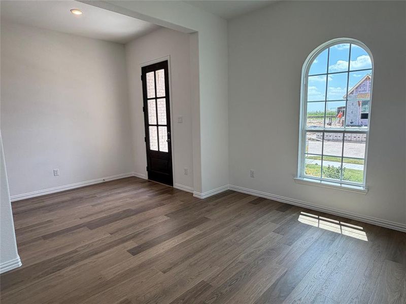 Spacious room featuring wood-finish flooring, crisp white walls, and a recessed ceiling light