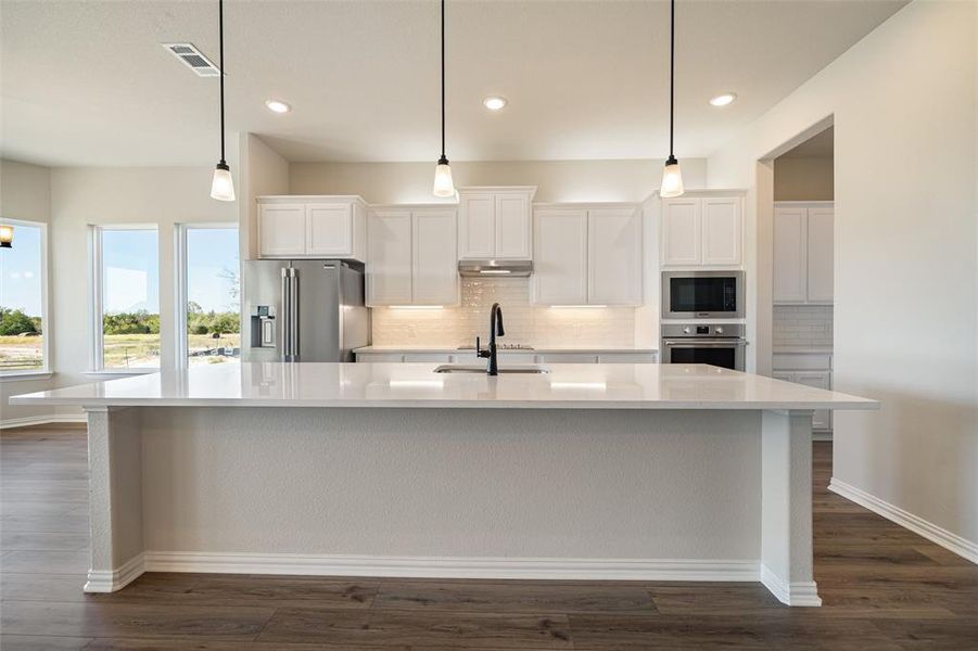 Kitchen with white cabinetry, tasteful backsplash, a large island, appliances with stainless steel finishes, and recessed lighting